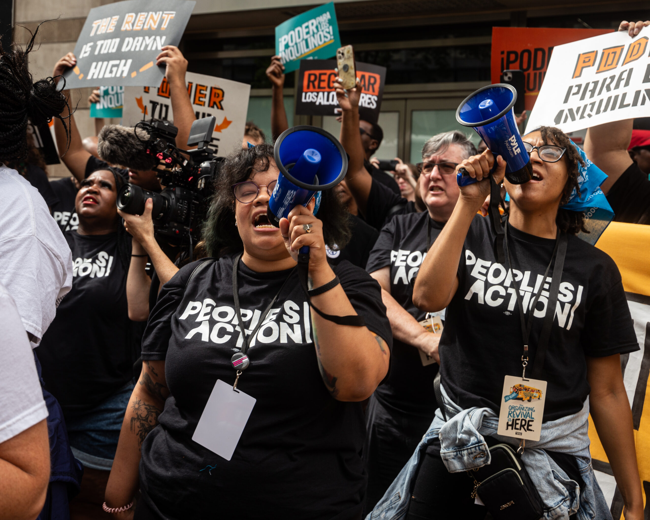 Group of activists with megaphones, cameras and several signs in Spanish and English.